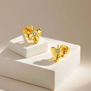 Nahaufnahme goldene Bienen-Ohrstecker mit Zirkonia auf weißem Schmuckständer präsentiert