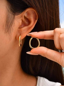 Close-up of a minimalist gold U-shaped hoop earring worn on an ear with a polished finish