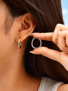 Close-up of minimalist silver U-shaped stainless steel earrings worn outdoors
