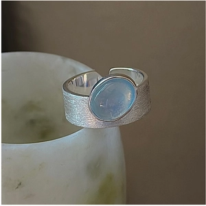 Detail of brushed silver adjustable ring with an oval light blue moonstone on a cup edge