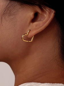Close-up of a model wearing a gold heart-shaped U-shaped hoop earring with a polished finish