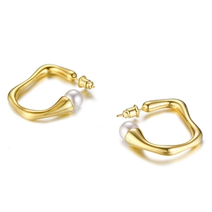 Macro detail of irregular gold wave earrings featuring elegant white pearls on white background