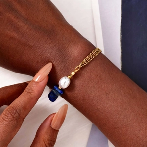 Détail du bracelet doré avec pierre de lapis-lazuli bleue et perle baroque élégante