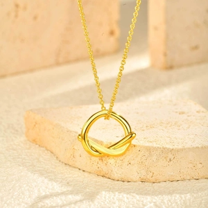 Collier minimaliste en or à double anneau entrelacé sur un bloc de pierre décoratif