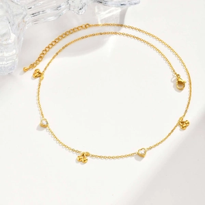Close-up of golden necklace with alternating cherry pendants and white zircon hearts