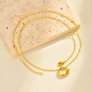 Détail d'un pendentif nœud géométrique doré minimaliste avec chaîne réglable et fermoir