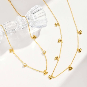 Detailed macro view of gold-tone necklace featuring cherry and heart pendants with white zircons