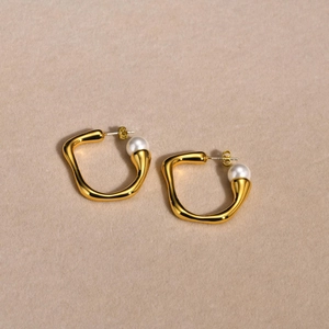 Detail of gold irregular geometric hoop earrings with elegant white pearl accents