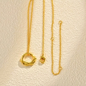 Détail d'un pendentif nœud torsadé doré minimaliste sur une chaîne à maillons fins