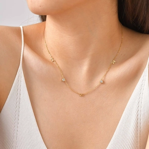 Close-up of golden bow and white rhinestone heart pendant on a fine neck chain