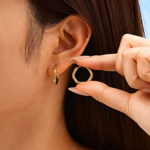 Minimalist gold-plated stainless steel U-shaped hoop earrings worn on a female earlobe