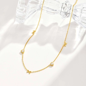 Detail of gold stainless steel necklace with sparkling heart charms and bows