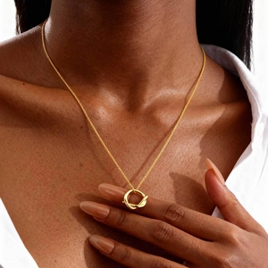 Collier minimaliste à pendentif nœud doré avec chaîne fine porté par un mannequin chic