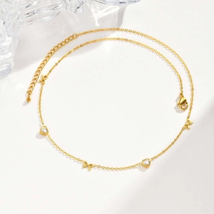 Detailed view of gold stainless steel necklace with heart crystals and bow charms