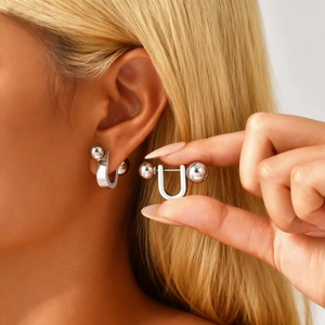 Detailansicht von U-förmigen Silberkugel-Ohrringen an einem Modell im minimalistischen Stil