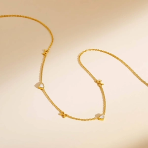 Detailed view of gold stainless steel necklace with crystal hearts and metal bows