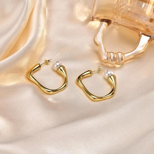 Chic irregular golden U-shaped earrings with pearls on silk champagne background