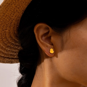 Boucles d'oreilles canard jaune en émail et finition or 18K sur l'oreille du mannequin