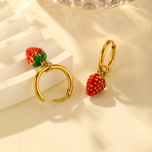 Close-up of gold stainless steel strawberry earrings with red enamel and leaf detail