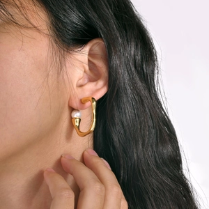 Irregular gold U-shaped earrings with round white pearl accent on female model