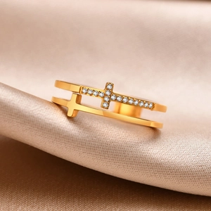 Macro d'une bague double croix dorée avec zircons sur du satin de soie élégant