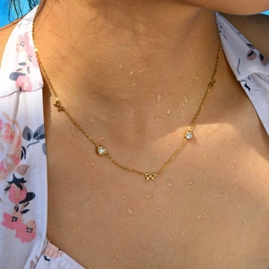 Golden stainless steel heart and bow necklace with white zircons on model neck