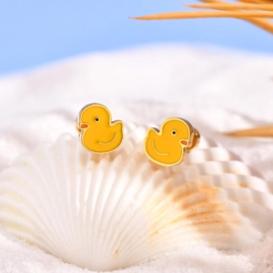 Détail de boucles d'oreilles canard en émail jaune sur un coquillage blanc de plage