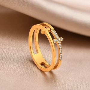 Détail d'une bague double croix dorée sertie de zircons sur fond de satin champagne