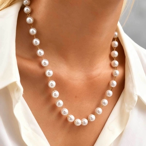 Close-up of elegant Y-shaped faux pearl necklace with gold chain on model's neck