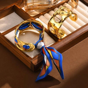 Detailed close-up of textured gold cuffs with vibrant geometric print silk scarf