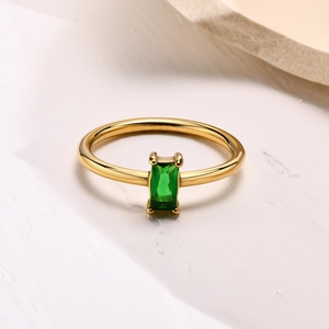 Macro detail of emerald cut green zircon set in 18k gold minimalist stainless steel ring