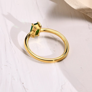 Close-up of gold stainless steel ring with rectangular green gemstone and four-prong setting