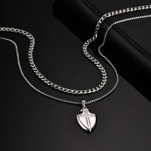 Détail du pendentif bouclier en acier avec croix en zircon sur miroir noir chic