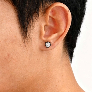 Detail of round white zircon stud earring with minimalist black metal claw setting