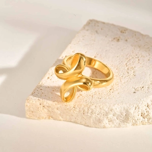 Polished gold irregular knot ring for women on stone background in minimalist style