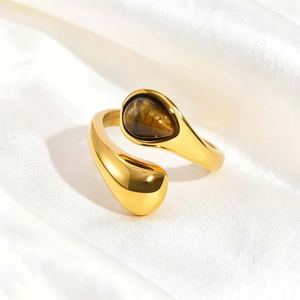 Macro detail of teardrop-shaped tiger eye stone and polished gold stainless steel ring