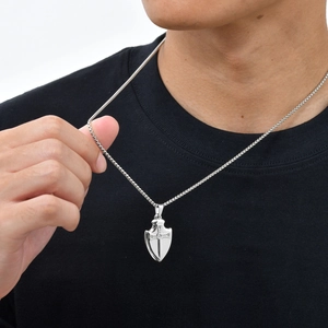 Gros plan d'un collier pendentif bouclier pour homme avec croix en zircone sur t-shirt