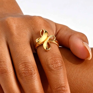 Close-up of a gold-plated bow ring on model's finger with a mirror-finish texture