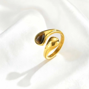 Macro shot of gold teardrop ring featuring a natural tiger eye stone on silk fabric