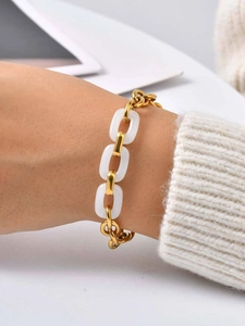 Close-up of golden stainless steel chain bracelet with white jade-like oval links on wrist