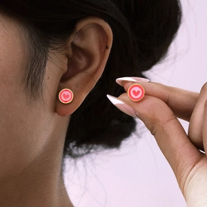 Vue détaillée de boucles d'oreilles cœur en émail rose avec monture dorée