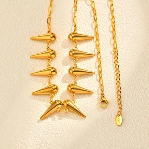 Détail des breloques goutte d'or et du poinçon K18 sur le collier en acier inoxydable