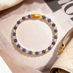 Detail of gold evil eye tennis bracelet with blue zircon and round crystal stones