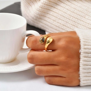 Golden teardrop tiger eye stone open ring shown on hand with coffee cup scene