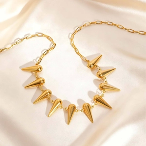 Collier à maillons trombone dorés avec pendentifs à pointes sur satin champagne