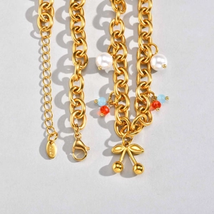 Détail de chaîne dorée avec pendentif cerise, perles et gravure K18 de luxe