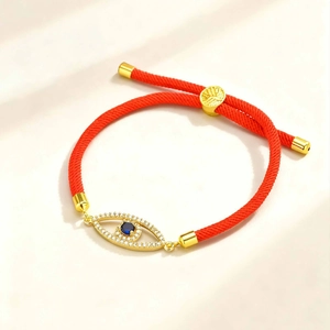 Detail of red braided Evil Eye bracelet with golden tree charm and blue zircon stones