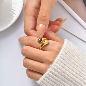 Close-up of a gold open ring with teardrop tiger eye stone on a model's hand