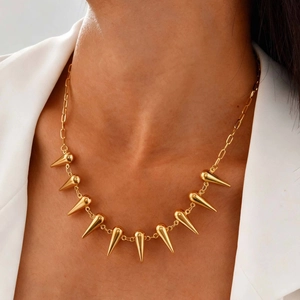 Gros plan d'un collier doré en acier inoxydable avec pointes coniques sur un mannequin