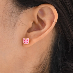 Gros plan de boucles d'oreilles papillon roses dorées portées par un mannequin